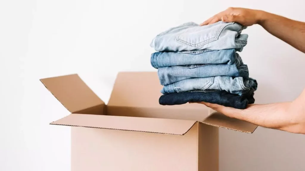 manos metiendo pantalones doblados una una caja de cartón